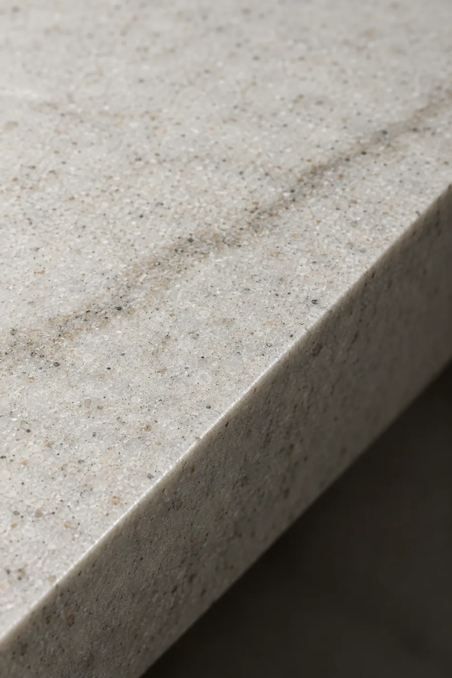 Close-up of a honed quartz slab edge with fine grey speckle